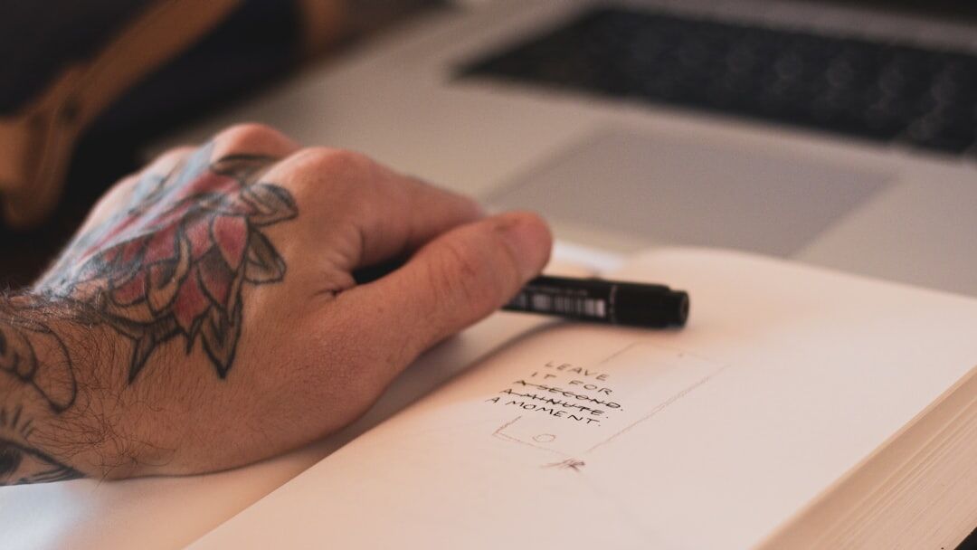 Person writing a script by hand next to a laptop with a story timeline
